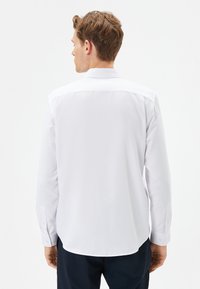 Witte long-sleeve shirt met een zachte textuur en knoopmanchetten. Heeft een klassieke kraag en een afgeronde zoom, ontworpen voor comfort.