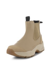Botín de tobillo impermeable beige con paneles laterales elásticos, suela de goma y tirador. Textura suave con detalle de costura decorativa.