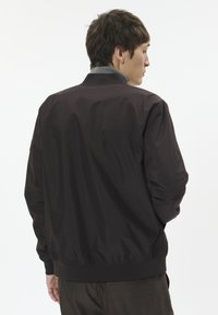 Must nahktagi stiilne bomberjakk, millel on sileda ja mati viimistlusega pind, soonikuga krae ning elastsed mansetid. Omab lõdvestunud lõiget ja minimalistlikku disaini.