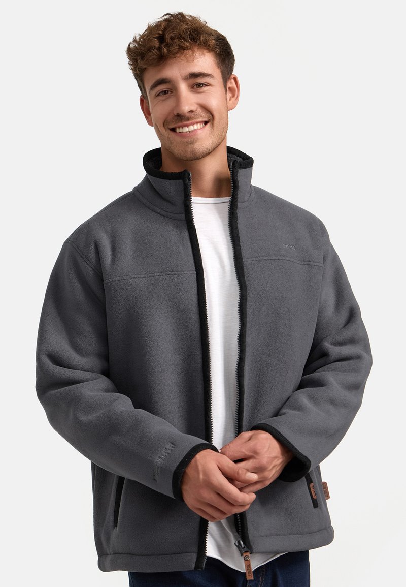 Chaqueta de forro polar gris con cuello alto, cierre de cremallera y detalles en negro. Presenta bolsillos laterales y una textura suave.