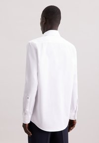 Witte lange mouwen shirt met een gestructureerd patroon, klassieke kraag, knoopmanchetten en een gebogen zoom. Geen zichtbare logo's of afbeeldingen.