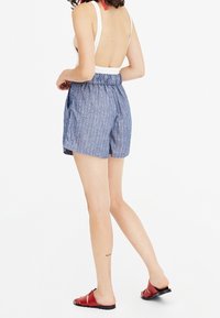Un short à rayures bleues et blanches avec une taille élastique, doté de poches latérales et fait d'un tissu léger.
