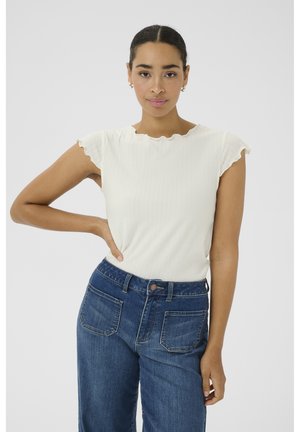 Haut blanc côtelé à manches courtes avec encolure froncée, associé à un jean en denim bleu taille haute avec deux poches arrière.