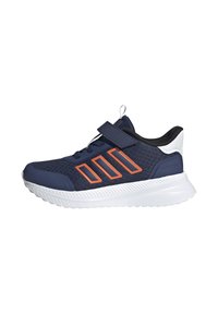 Zapatilla deportiva azul marino con acentos naranjas, hecha de malla y materiales sintéticos. Cuenta con una correa de velcro y una suela blanca texturizada.