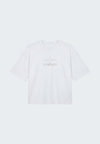 T-shirt blanc à manches courtes avec un col rond et un motif en forme d'étoile composé de petits points noirs au centre de la poitrine.