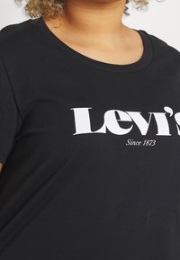 Camiseta de algodón negra con cuello redondo y mangas cortas, con gran texto blanco "Levi's" y detalle "Desde 1873" en el frente.