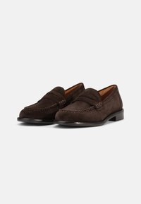 Brown suede loafers with a stitched moccasin design, flat leather sole, and a raised seam across the vamp for added detail.