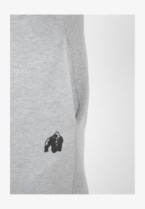 Grijze sweatpants hebben een zwart gorilla-logo op de rechterheup, gemaakt van een zachte katoenmix met een gladde textuur.