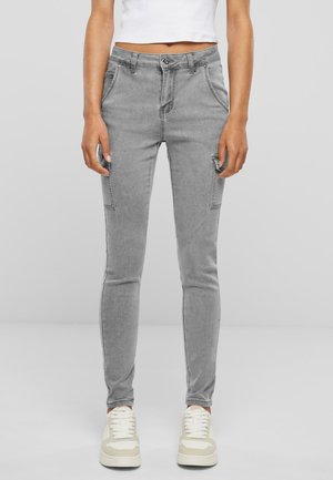 Grijze slim-fit jeans van gladde stof, met een vijf-pocket ontwerp en zichtbare stiksels. Gecombineerd met lichtgekleurde sneakers.