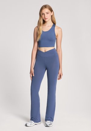 Crop top sportivo blu e leggings a campana abbinati realizzati in tessuto elastico. Il top presenta un ampia scollatura; i leggings hanno una finitura liscia.