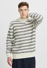Pulover tricotat cu dungi crem și bleumarin, având un guler și manșete ribbed, caracterizat printr-o țesătură moale și texturată, cu mâneci lungi.