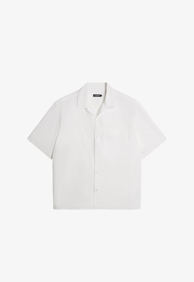 Biela blúzka s krátkym rukávom, mäkká textúra, gombíkový predný otvor, rozšírený golier, jedno vrecko na hrudi, voľný a pohodlný strih. Jednoduchá, bez vzorov.