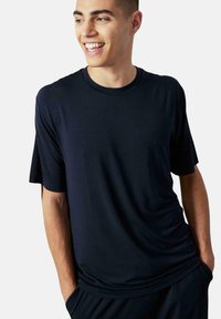 Camiseta de manga corta azul marino con cuello redondo, textura suave, corte relajado y costuras visibles, combinada con pantalones a juego.