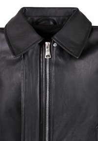 Giubbotto di pelle nera con un ampio colletto, zip silver, texture liscia e dettagli di cucitura visibili lungo la parte anteriore.