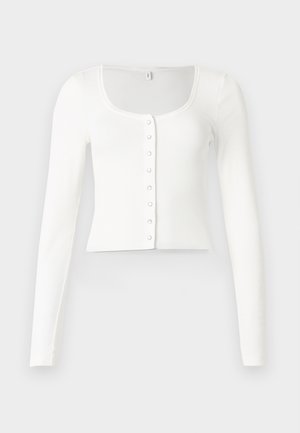 Witte geribbelde cropped cardigan met lange mouwen, een ronde hals en acht drukknoopjes aan de voorkant, plat gelegd op een lichte achtergrond.