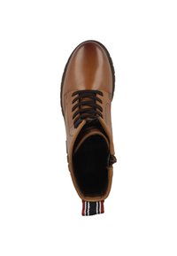 Botín de cuero marrón con punta redondeada, cordones negros y una lengüeta con rayas. La suela tiene textura para un mejor agarre.