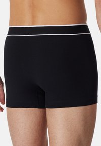 Boxer in cotone nero realizzati in tessuto morbido, con una vita elastica a strisce bianche e bordi senza cuciture per il massimo comfort.