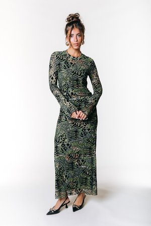 Abito a maniche lunghe e aderente di colore verde con motivo animalier. Tessuto trasparente e testurizzato. Abbinato a tacchi neri a punta.