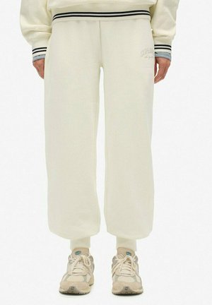 Cream-colored cropped sweatpants with a drawstring waistband, featuring black and white striped accents and soft, textured fabric.