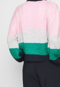 Strikket sweater med horisontale striber i pink, hvid, grøn og navy. Kropet er kortere med afslappede ærmer og struktureret stof.