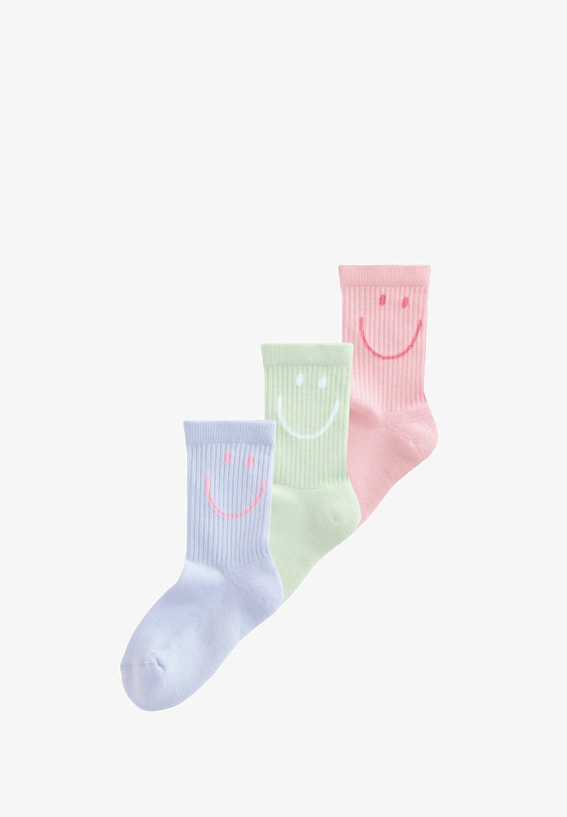 Trois chaussettes côtelées mi-mollet en bleu pastel, vert et rose, chacune avec un grand visage souriant près du haut.