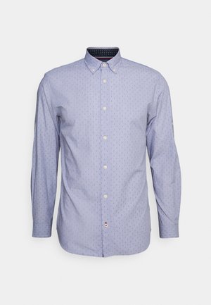 Chemise bleu clair à manches longues avec un petit motif vertical à pois et un col boutonné sur un fond blanc uni.