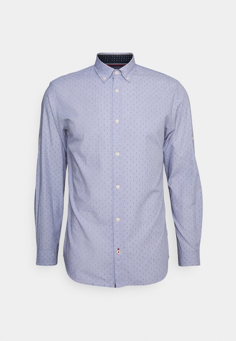 Chemise bleu clair à manches longues avec un petit motif vertical à pois et un col boutonné sur un fond blanc uni.