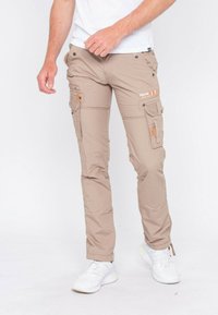 Pantalons cargo beige en tissu léger avec plusieurs poches, fermetures éclair et accents orange, présentant une coupe droite et un design simple.