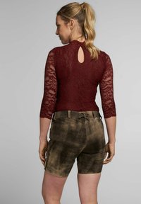 Burgunderfarbener Spitzen-Bodysuit mit 3/4-Ärmeln und einem Schlüsselrücken, kombiniert mit braunen Wildleder-Shorts mit Kordelzug und Taschen.