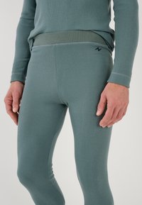 Comfortable, light teal thermal leggings with a soft ribbed texture, stretchy waistband, and subtle branding on the side.