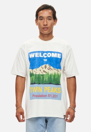 Witte katoenen T-shirt met een grafische print van bergen, bomen en "Welkom in Twin Peaks" in blauw en geel. Korte mouwen, relaxed fit.