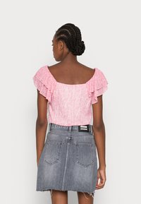 Top rosa com padrão, com mangas franzidas e design de costas quadradas, combinado com uma saia de ganga cinza desbotada com bainha desfeita e bolsos traseiros.