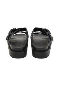 Paire de sandales à plateforme noires avec des brides pailletées et des boucles argentées, vues de dos sur un fond blanc.