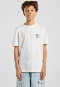 White cotton t-shirt with short sleeves and ribbed neckline. Features a green graphic design on the left chest area.