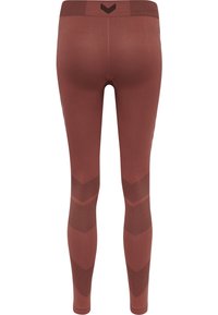 Fitte leggings in een roestkleur met gestructureerde zwarte accenten. Kenmerken verticale en horizontale gestreepte patronen langs de zijkanten.