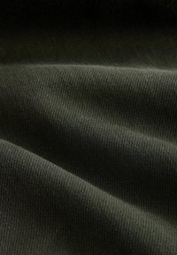 Dark olive green fabric with a smooth texture and fine ribbed pattern, showing folds and creases typical of soft knitted materials.
