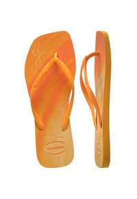 Oranžid flip-flopid, millel on tekstureeritud tallad, õhukesed rihmad ja gradientdisain. Basseini sees on esitatud reljeefne logo.