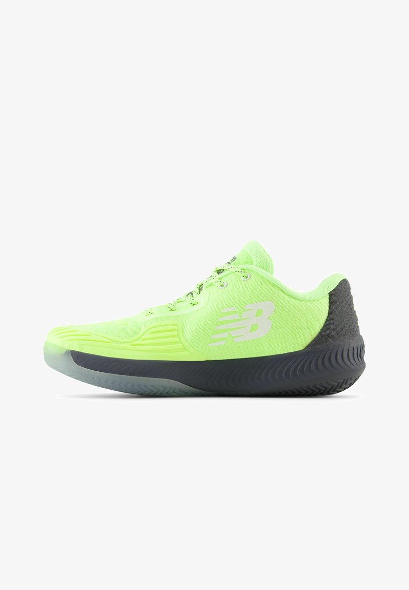 Zapatilla deportiva de color verde neón con parte superior de tejido texturizado, talón gris y suela de goma negra. Presenta un logo distintivo y acentos con patrones.