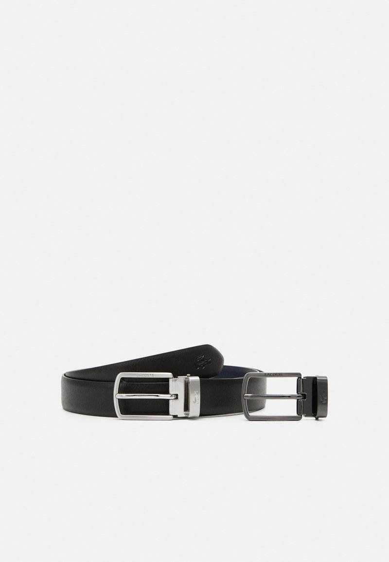 Cintura in pelle nera con una texture liscia, dotata di una fibbia argentata lucida e un accento con logo. Il design è semplice e funzionale.