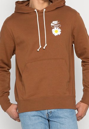 Brun Nike-hoodie med hvide snore, forlomme og et brystlogo med en mælkebøtte og teksten "From Beaverton with love."