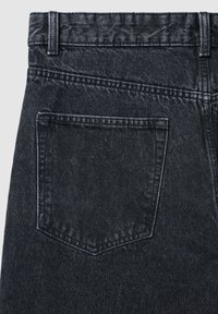 Jeans in denim nero con tasca posteriore con bordo superiore arrotondato, cuciture visibili e finitura testurizzata. Accento in vera pelle sulla vita.