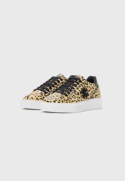 Nízké tenisky s leopardím vzorem, černými šňůrkami, černým patním poutkem a bílou silnou gumovou podrážkou na jednobarevném pozadí.