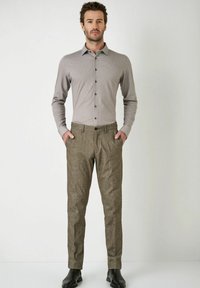 Overhemd met knopen in een lichtbruine, gemusterde ontwerpen, gecombineerd met getextureerde, donkerbruine broeken en zwarte schoenen. Slank fit, casual stijl.