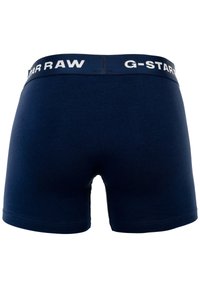 Boxers de algodón azul marino con una cinturilla elástica blanca que lleva el logotipo "G-STAR RAW". Textura suave y diseño ajustado.