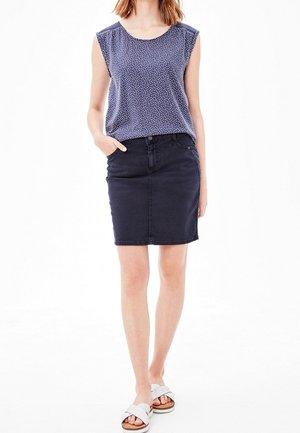 Ärmelloses marineblaues Oberteil mit weißen Punkten und rundem Halsausschnitt, kombiniert mit einem taillierten Jeansrock. Verfügt über Seitentaschen und eine strukturierte Materialoberfläche.