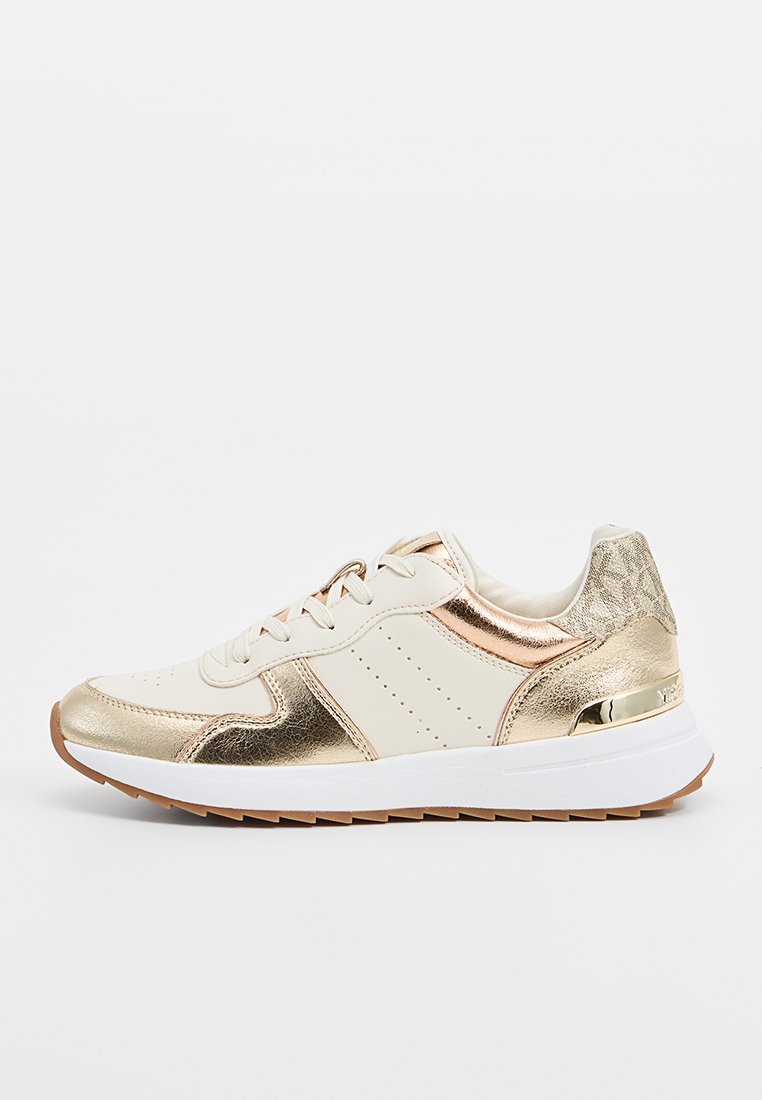 Baskets sportives avec une tige en cuir crème, des accents métalliques dorés, des détails perforés et une semelle en caoutchouc blanche et beige.