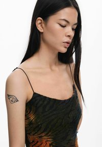 Camisola nera e arancione con motivo a strisce, dotata di sottili spalline e realizzata in un tessuto testurizzato che riproduce un design a strisce di tigre.