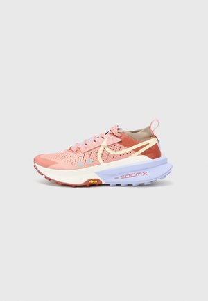 Nike løbesko med en pink overdel, perforerede sektioner og en beige hæl. Har lyseblå detaljer og en tyk hvid sål med røde og gule elementer.