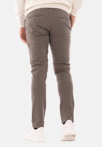 Pantaloni di cotone grigi con una vestibilità slim, due tasche posteriori e una texture liscia. Abbinati a scarpe da ginnastica bianche per un look casual.