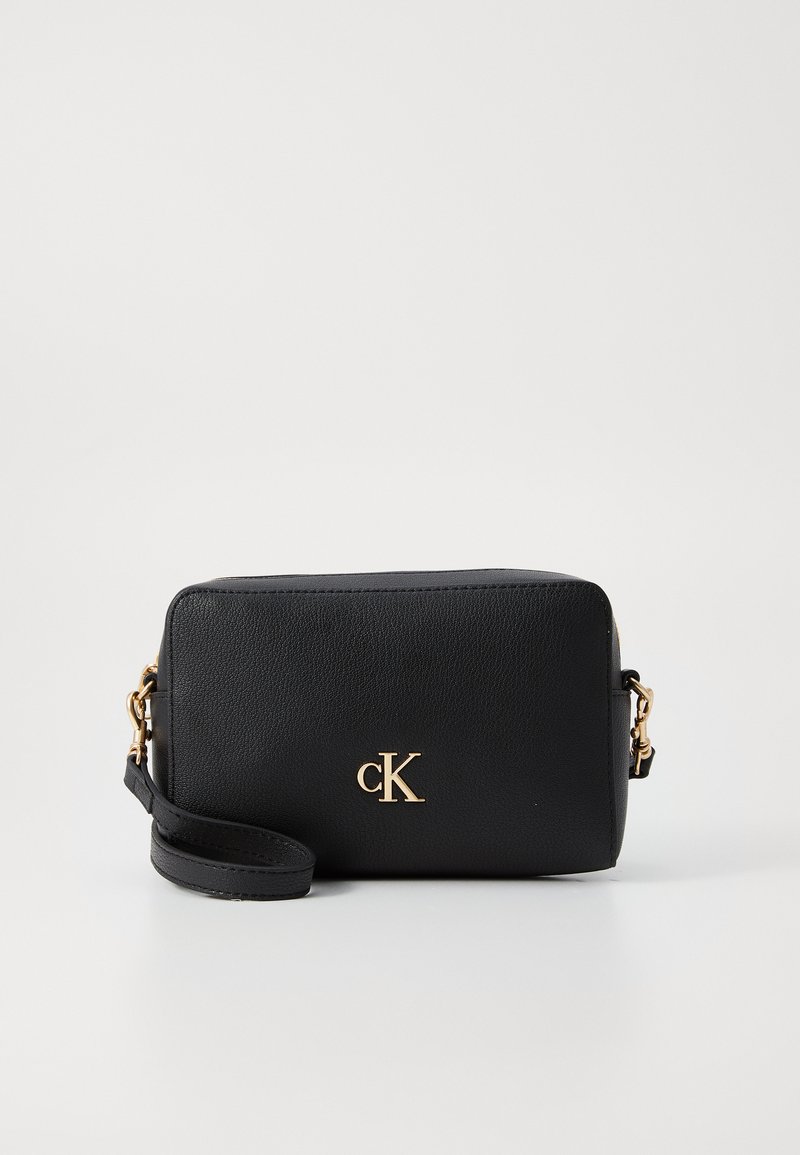 Black rectangular handbag made of textured leather, featuring a gold 'cK' logo, detachable strap, and zip closure.